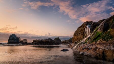 A seascape sunset with a waterfall at the beach. Humboldt County, California.の写真素材