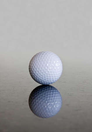 Single golf ball reflecting off a shiny marble surfaceの写真素材