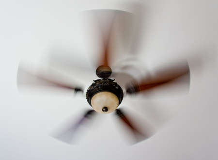 An ornate spinning ceiling fan with glass lightの写真素材