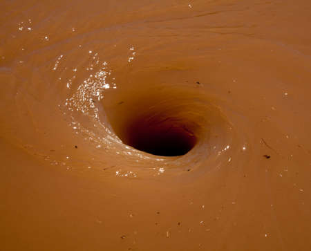 Deep brown flood water in river swirling into a whirlpoolの写真素材
