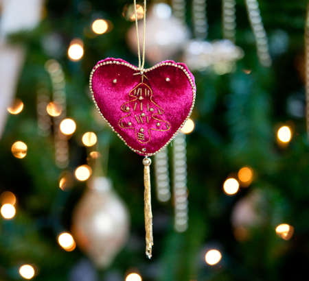 Close up of red velvet heart ornament in front of out of focus christmas decorationsの写真素材