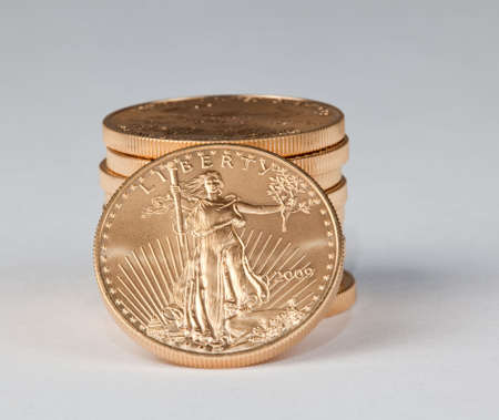 Vertical stack of ten gold coins with a single one facing the camera with the Liberty side visible