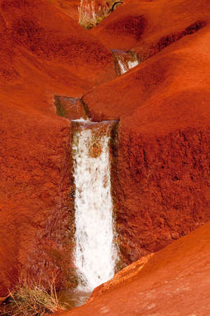 Water running in a stream down the bright red dirt of Waimea Canyon in Kauaiの写真素材