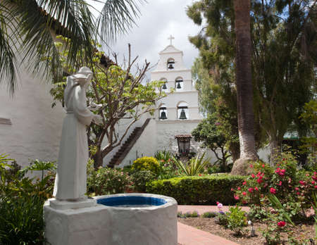 Garden of San Diego mission with bells framed by saint statue and wellの写真素材