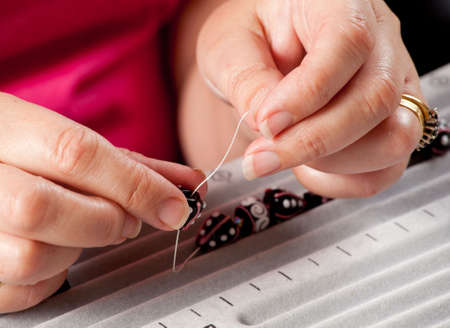 Close up of threading beads onto wire to make artistic bead necklace or bracelet