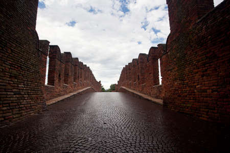 Ponte CastelVecchio in Verona with battlements against the cloudy skyの写真素材
