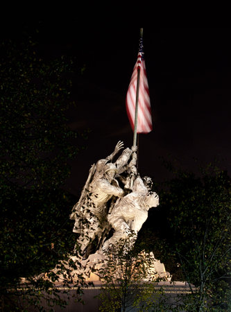 Statue commemorating Iwo Jima at night lit by floodlights and seen through the trees and branchesのeditorial素材