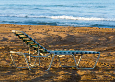 Old plastic sun lounger on a sandy beach by the seaの写真素材