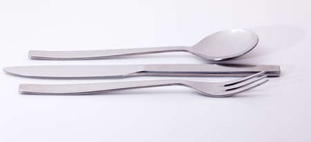 Knive fork and spoon from modern stainless steel design isolated against white and reflecting white lightの写真素材