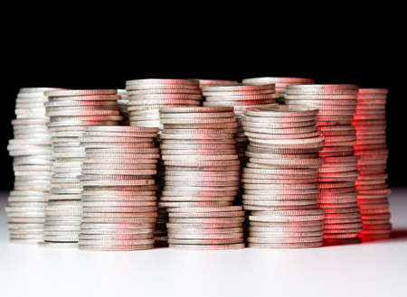 Many stacks of old silver dimes face on to camera and illuminated with red lightの写真素材
