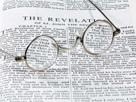 Old fashioned round reading glasses laying on a page from the bible on the revelationの写真素材