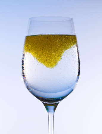 Olive oil being stirred in a large wine goblet forming golden bubbles in the liquidの写真素材