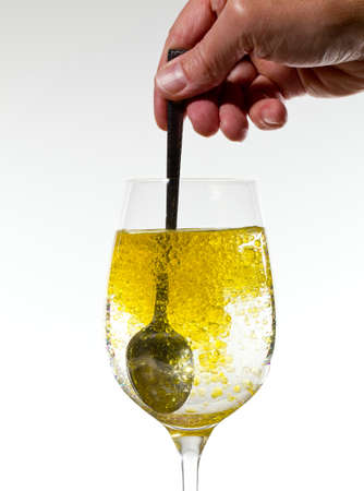 Olive oil being stirred in a large wine goblet forming golden bubbles in the liquidの写真素材