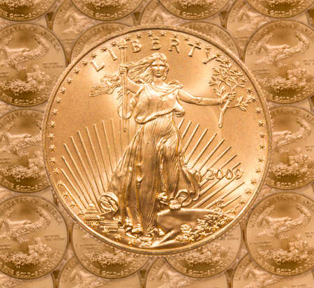 Gold Eagle one ounce coins in a patterns and stacked on each row with a single Liberty coin on the topの写真素材