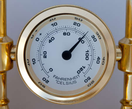 Gold thermometer measuring centigrade and farenheit and fixed in a brass holder