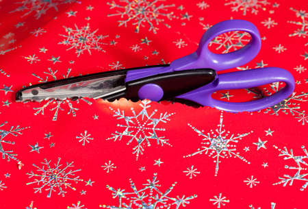 Christmas paper being cut by special scissors to create pattern in the cut edgeの写真素材