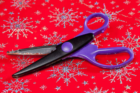 Christmas paper being cut by special scissors to create pattern in the cut edgeの写真素材