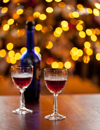 Cut glass sherry or port glasses in front of an out of focus christmas tree with blue bottleの写真素材
