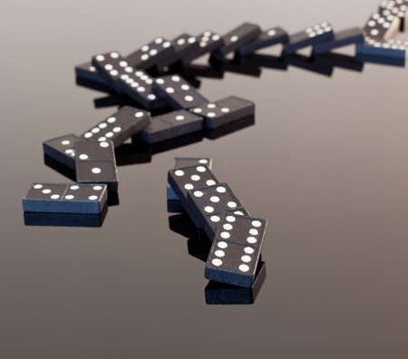Macro image of dominos on a black reflactive surface and collapsed in pile