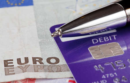 Macro of debit card and pen on top of euro note to illustrate currency crisis in Europe
