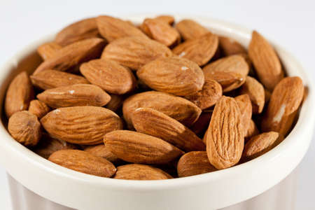 Pile of almond nuts in a porcelain bowl ready as a snackの写真素材