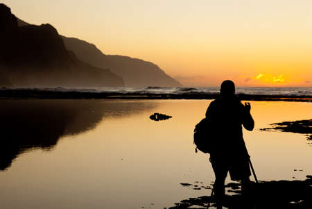 Silhoutte photographer of Na Pali coast by Ke'e beach in Kauai at sunsetの写真素材