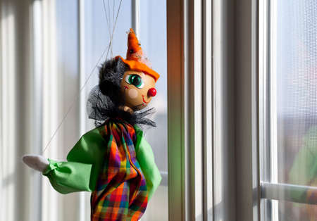 Puppet or marionette hanging in window and gazing outside into sunlit exteriorの写真素材