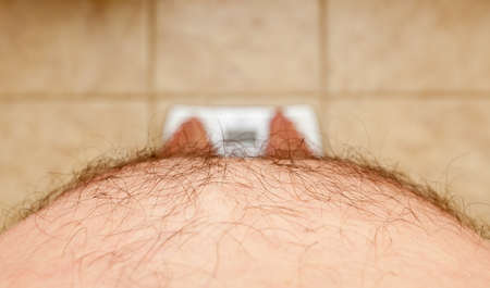 Close up of stomach of large hairy man standing on bathroom scalesの写真素材