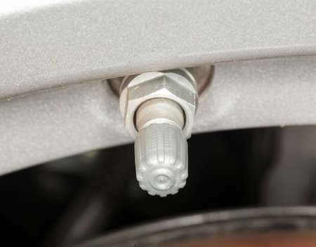 Silver colored tyre pressure valve on alloy wheel of carの写真素材