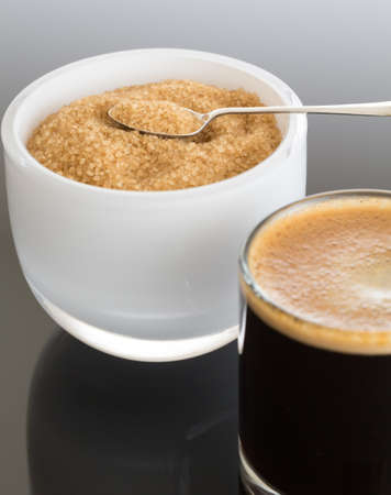 Black expresso coffee in small glass cup with sugar in white bowl reflectingの写真素材
