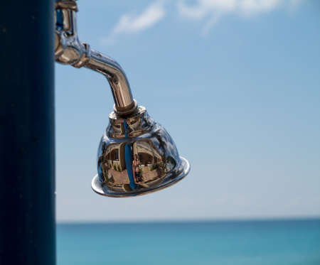 Reflections in a chrome silver shower head by beach with hotel reflectedの写真素材