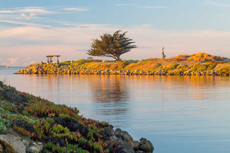 Mermaid statue playing flute by unknown artist at entrance to Ventura Harbor at sunrise