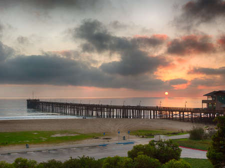 Pier at Ventura coast in California as the sun is setting over calm Pacific oceanの写真素材