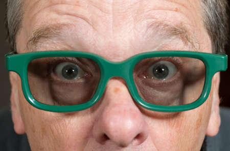 Senior male with shocked expression watching movie in 3d glasses with tight focus on face and eyes
