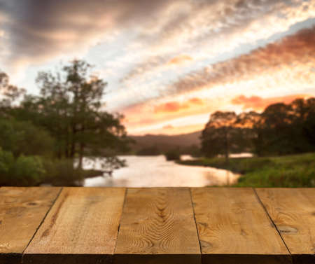 Wood pier or walkway or an old wooden table with blurred image of lake district in England as...