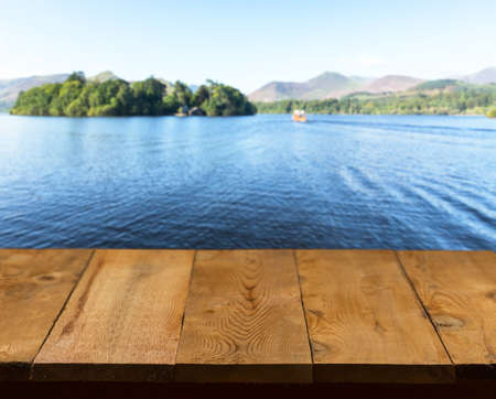 Wood pier or walkway or an old wooden table with blurred image of lake district in England as...