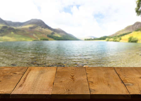 Wood pier or walkway or an old wooden table with blurred image of lake district in England as backgroundの写真素材