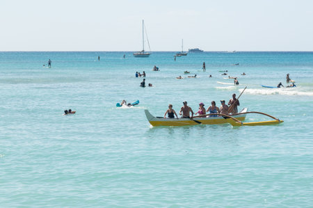 WAIKIKI, HI - JANUARY 20: Tourists in traditional Hawaiian canoe make for shore on 20 January 2012....