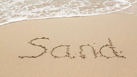 Sand drawing on warm beach by ocean surf in Caribbean spelling Sandの写真素材