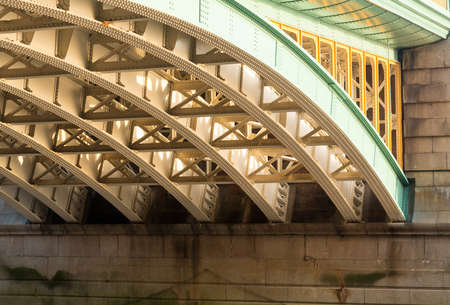 Girders supporting Southwark Bridge across the Thames river in London with setting sun lighting the painted ironworkの写真素材