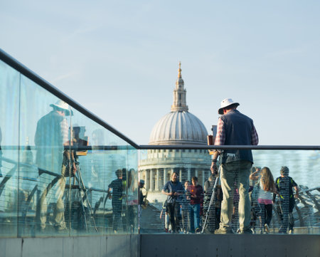 LONDON, UK - 23 APRIL: Londoners walk home from St Pauls past artist on 23 April 2013. The dome at 365 feet high towers over Millenium Bridgeのeditorial素材