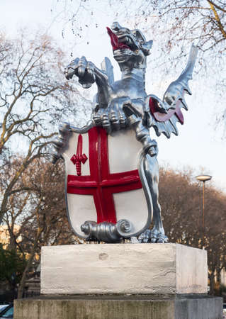 Dragon with red cross on shield marking the boundary of the City of London in England by roadsideの写真素材