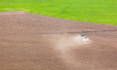 Tractor plowing or ploughing field of soil in dry conditions in southern germany in Neckar valley