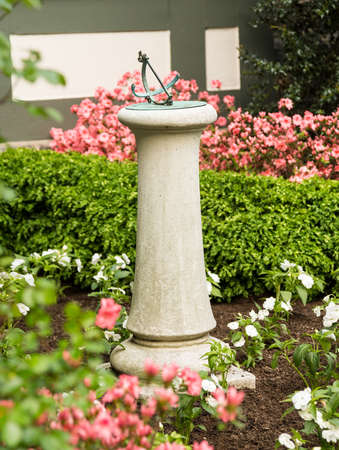 Concrete or stone bronze sundial in flower bed garden of old homeの写真素材