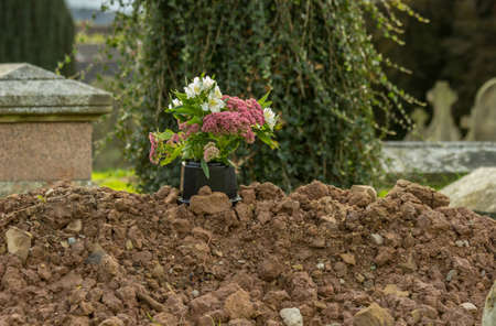 Freshly dug grave in cemetery or graveyard with pile of dirt or soil from ground piled highの写真素材