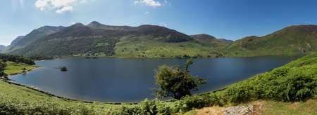 Panorama of the Lake District hills surrounding Crummock Water framed by the trees on the lakeside. Idyllic image from the English Lakesの写真素材