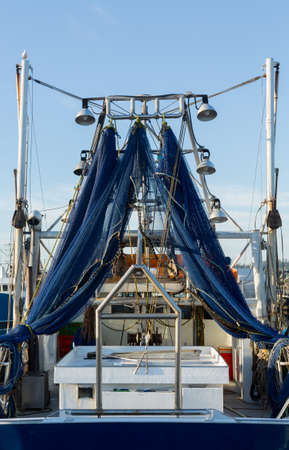 Large fishing boat in blue netting fishing nets hanging to dry