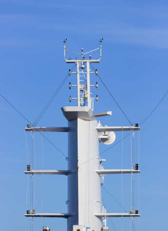 Communication tower or mast on large cruise ship with aerials and antennae against blue sky