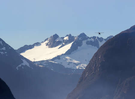 plane flying into Milford Sound on South Island of New Zealand in early morningの写真素材