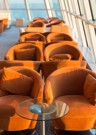 Row of cushioned seats or chairs and towel by high glass window looking out to sea with horizon in the distanceの写真素材